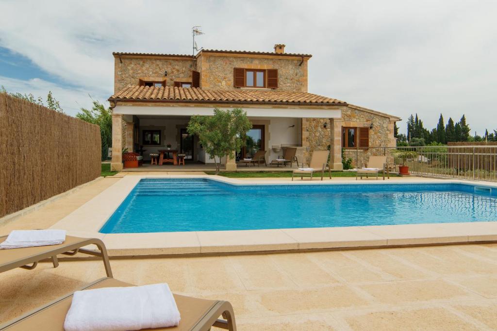 a villa with a swimming pool in front of a house at Carrusillo in Lloseta