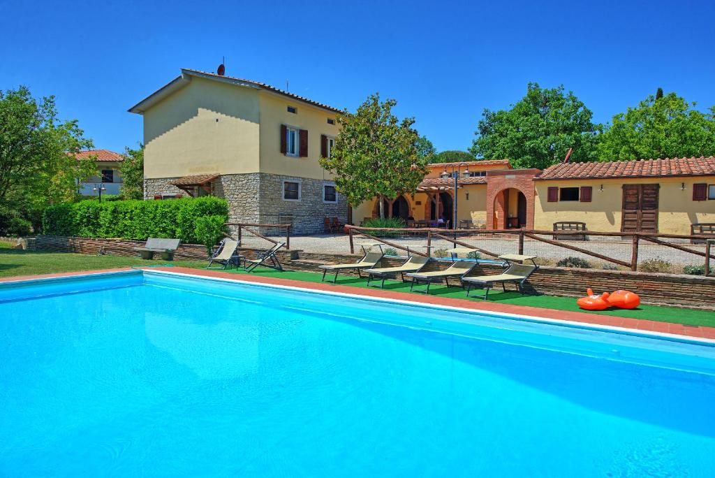 a large swimming pool in front of a house at Zeffiro by PosarelliVillas in Cortona