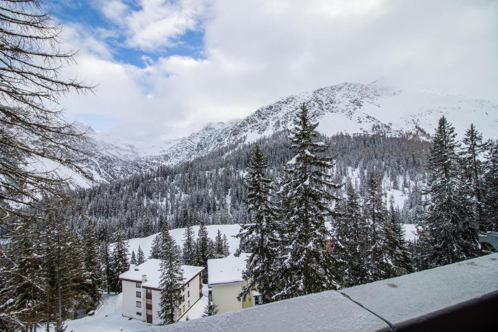 einen schneebedeckten Berg mit einem Gebäude und Bäumen in der Unterkunft Miraflor Angela by Arosa Holiday in Arosa