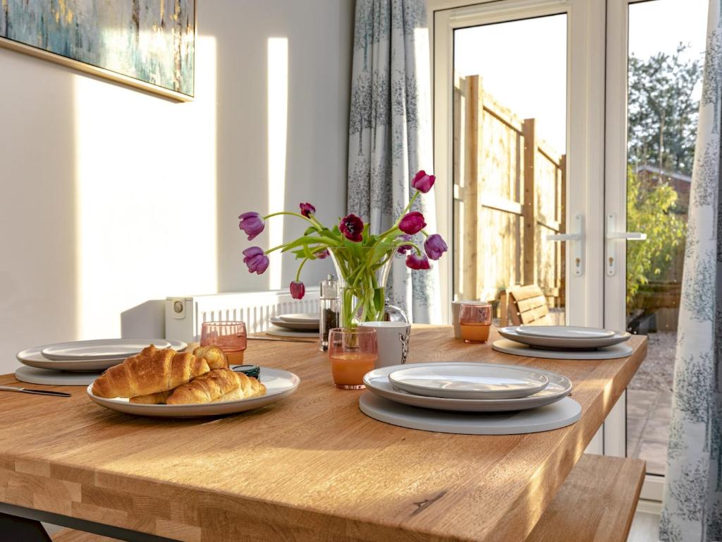 a wooden table with croissants and plates on it at Pass The Keys Stylish brand new two bedroom house, close to town in Ludlow