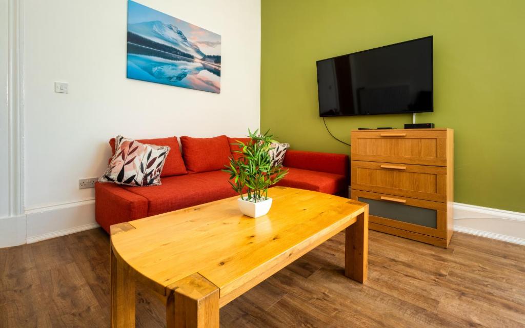 a living room with a red couch and a wooden coffee table at Dalhousie Upper in Glasgow