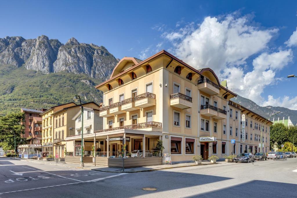 a building on a street in front of a mountain at Albergo Milano in Boario Terme