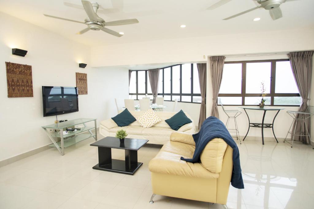 a living room with a couch and a tv at Sri Sayang Seaview Holiday Home in Batu Ferringhi