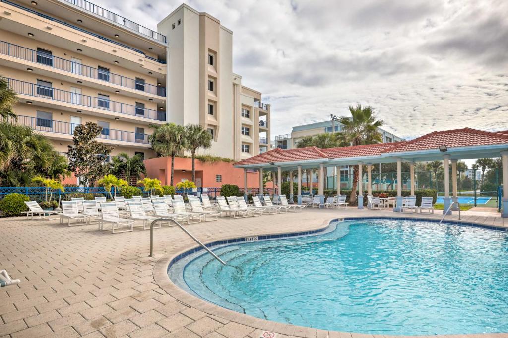 una piscina con sillas y un edificio en Coastal Condo with Balcony, Outdoor Pool Access en New Smyrna Beach
