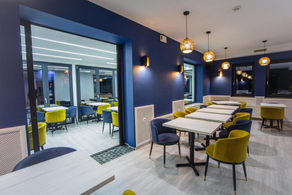 a dining room with tables and yellow chairs at Hotel Viktória in Sárvár