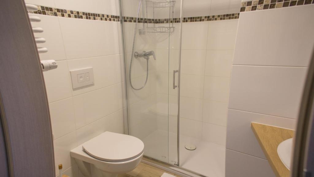 Compact tiled bathroom with glass shower enclosure, wall-mounted toilet, and wood-effect countertop.