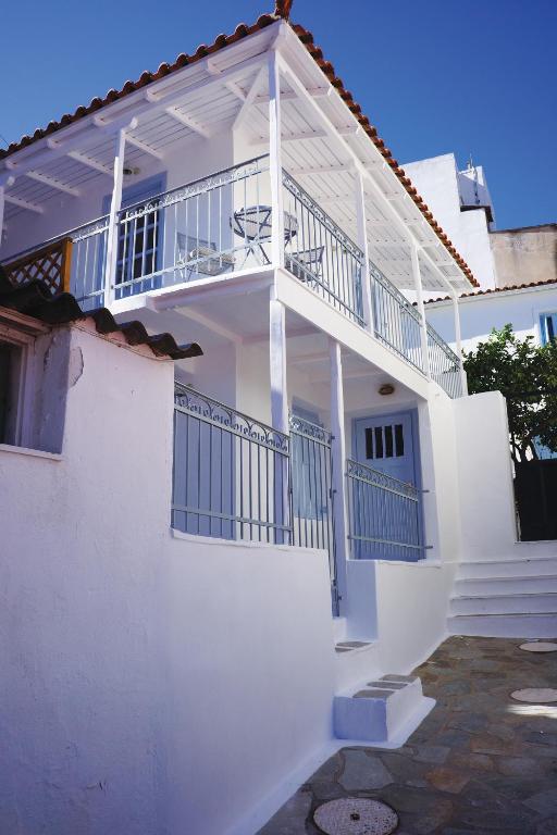 a white house with a balcony with blue railing at The Guest House in Skiathos