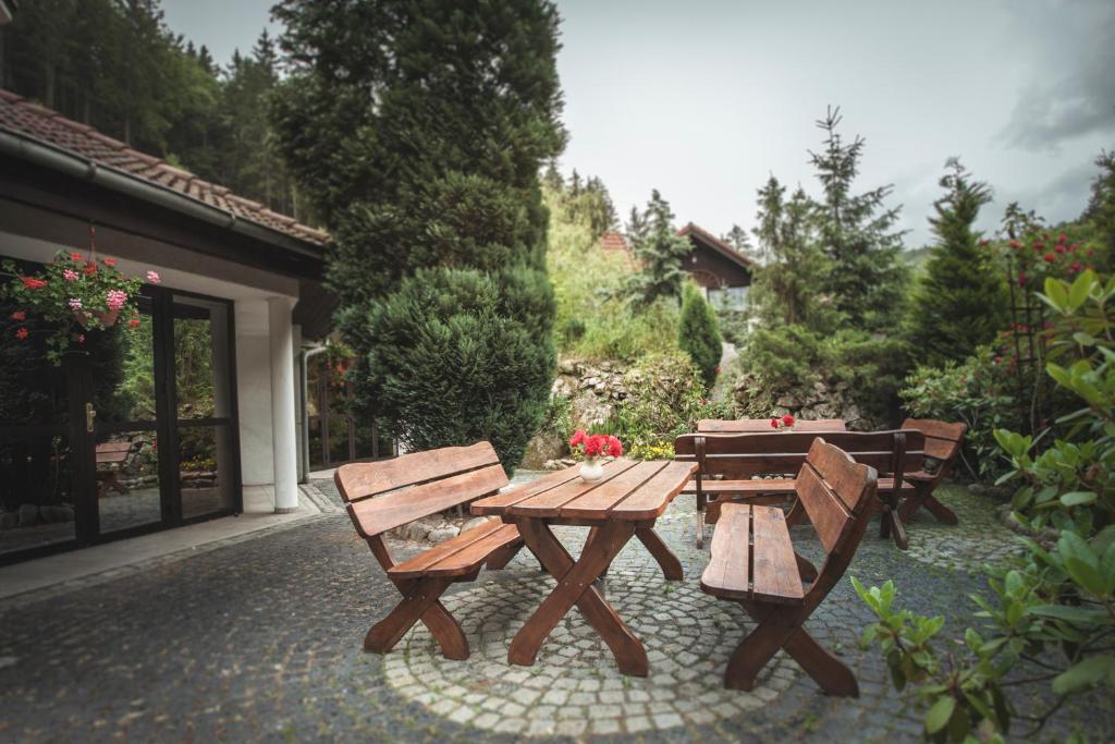 Wooden picnic tables and benches on stone courtyard surrounded by lush greenery and flowers.