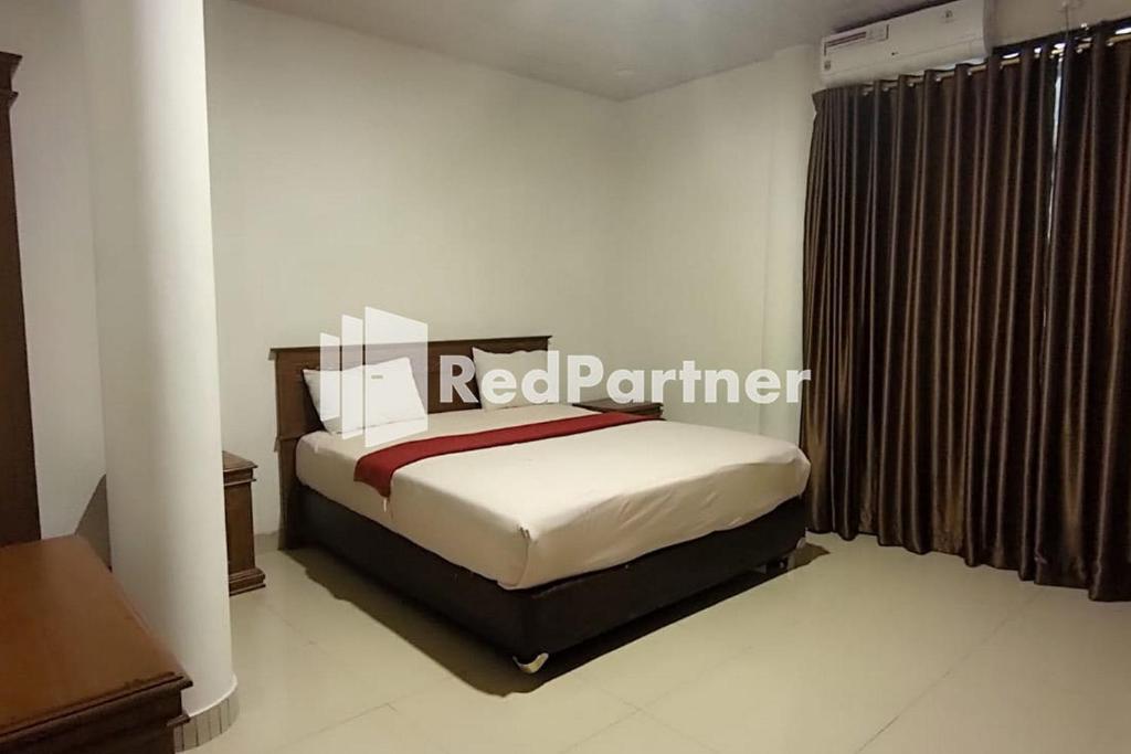 a bedroom with a bed with a red perimeter sign on it at Hotel Abna Sangatta Mitra RedDoorz in Sengata