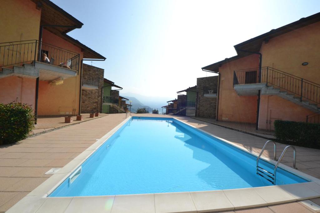 uma grande piscina azul entre dois edifícios em La casa di Gabry in residence con piscina comune em Tavernola Bergamasca