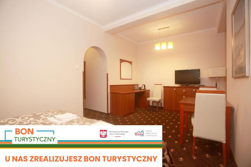 een kamer met een bed, een bureau en een televisie bij Restauracja Noclegi Ruczaj Czesława Worwa in Nowy Targ
