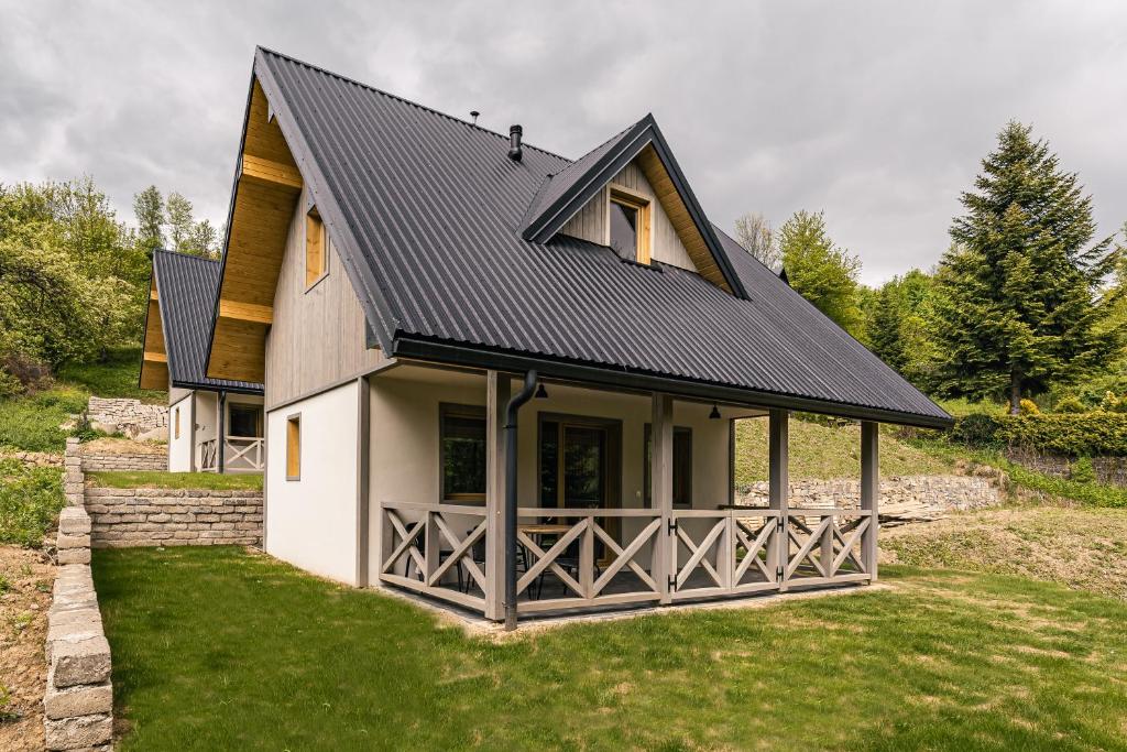 une maison avec un toit noir sur une cour verdoyante dans l'établissement SZARE DOMKI Szczawnica, à Szczawnica