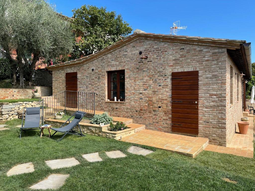 un bâtiment en briques avec une terrasse et une chaise dans une cour dans l'établissement Oliveta del Verde Appartamento con Grande Giardino 500mt dal Centro, à Sienne