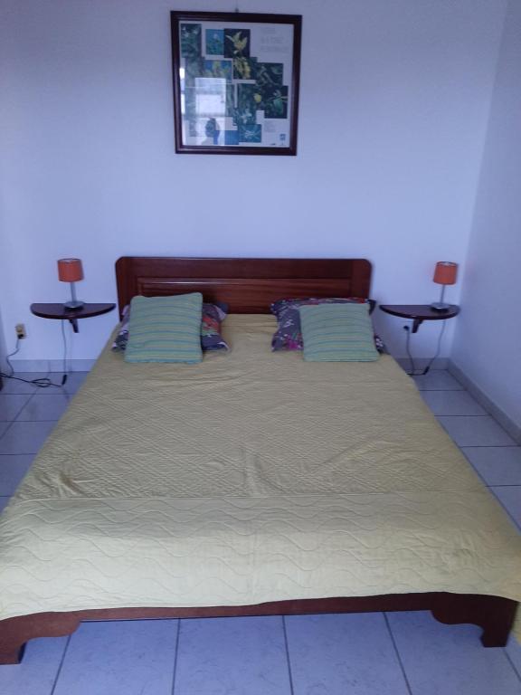 uma cama grande num quarto com duas mesas em Le Palmier em Saint-Philippe