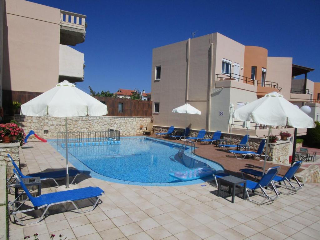 a swimming pool with chairs and umbrellas next to a building at Anna Αpartments II in Agia Marina Nea Kydonias