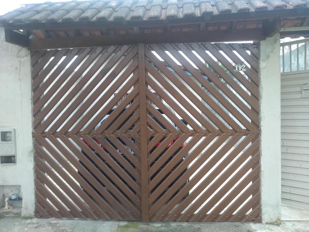 a wooden garage door with a roof on top at Casa de praia Indaiá Bertioga in Bertioga