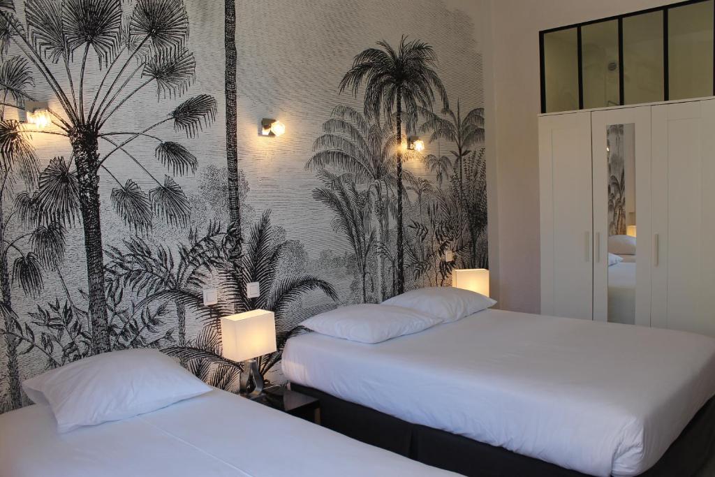 two beds in a room with palm trees wallpaper at Hotel Les Palmiers in Sainte-Maxime