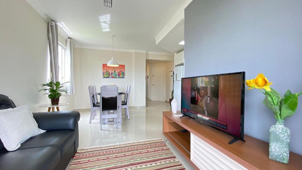 een woonkamer met een grote flatscreen-tv bij Aconchegante Apartamento na Praia de Bombas com ótima localização. in Bombinhas