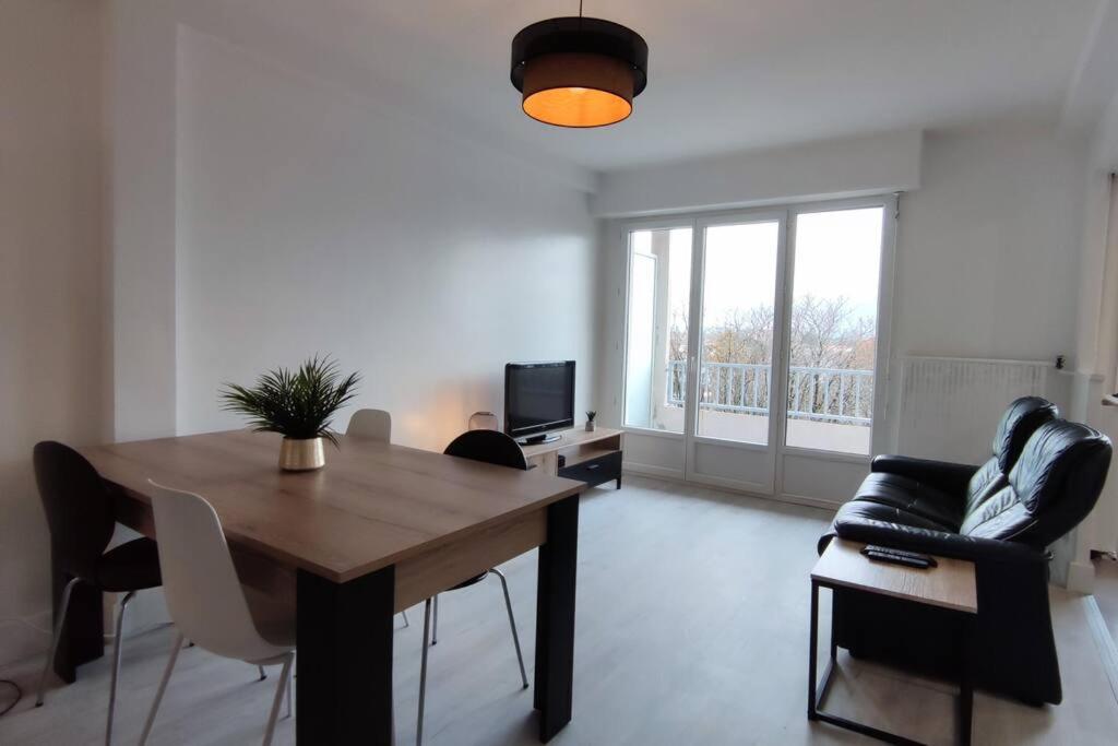 a living room with a wooden table and a couch at Superbe appartement avec vue sur les Pyrénées in Tarbes