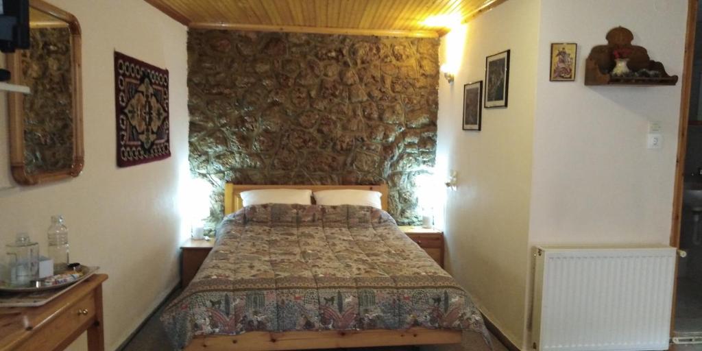 1 dormitorio con cama y pared de piedra en Country Style Room at the Center of Arachova, en Arachova