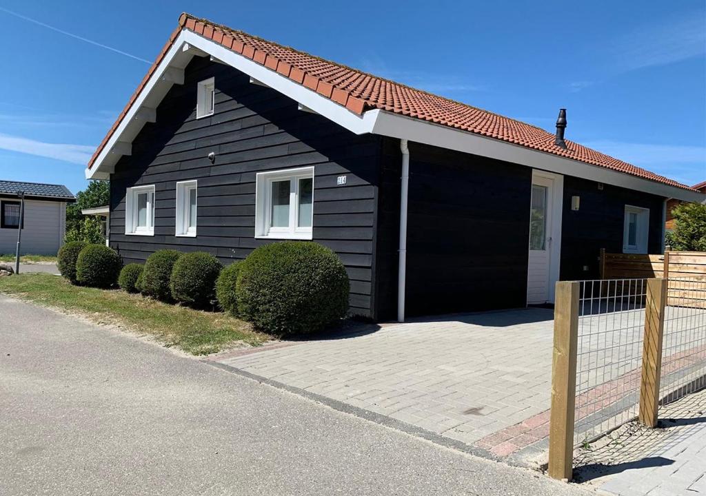 une maison noire avec une clôture devant elle dans l'établissement Chaletparc Krabbenkreek Zeeland - Chalet 214, à Sint-Annaland