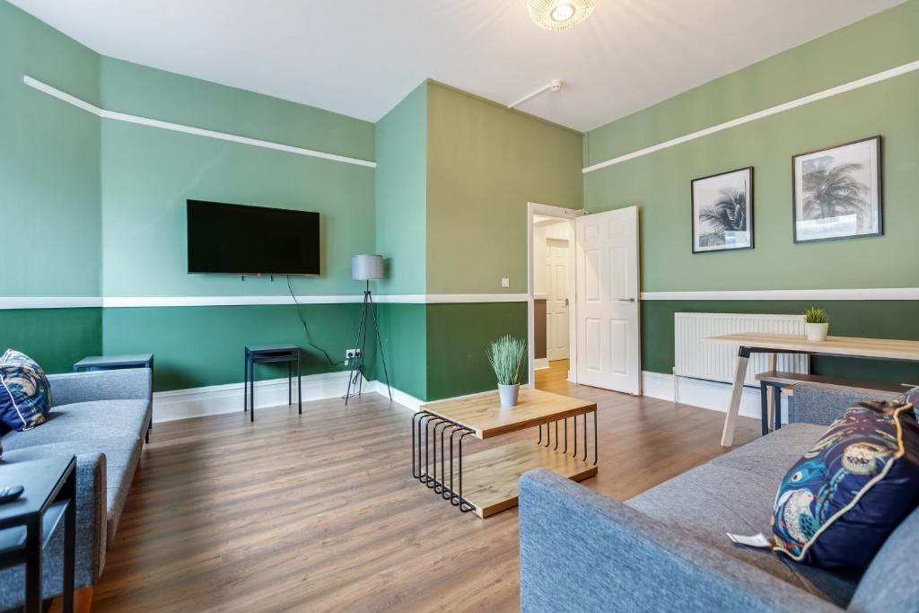 a living room with green walls and a tv at Queen Street Apartments by Sasco in Blackpool