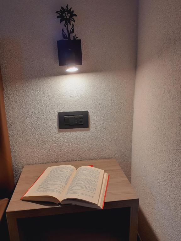 een open boek op een houten tafel met een licht bij Appartamenti Florin in Livigno