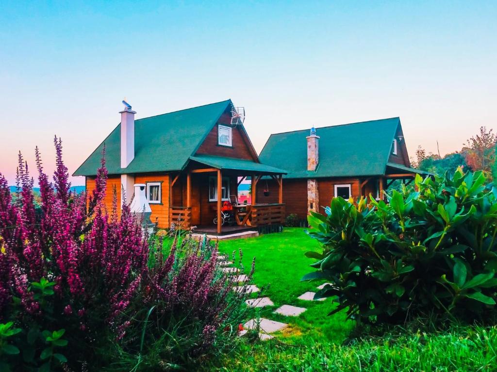 uma cabana de madeira com um telhado verde e algumas flores em Domek BB em Podgórzyn