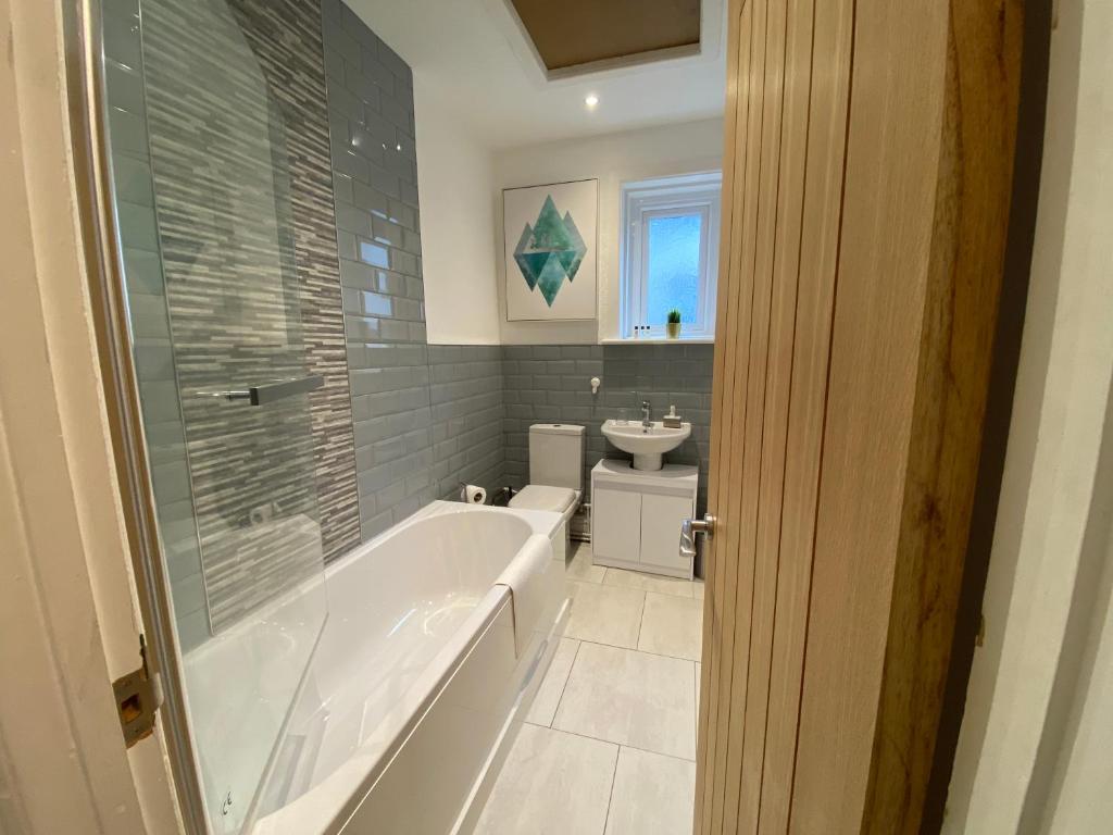 a bathroom with a tub and a sink at Judah Suites by Koya Homes - TV Bed Apartment, Central High Street, Free Parking in Barry