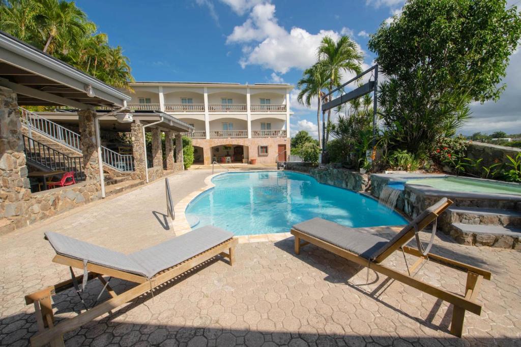 - une piscine avec une chaise et une maison dans l'établissement Lazy Parrot Inn & Mini Resort, à Rincon