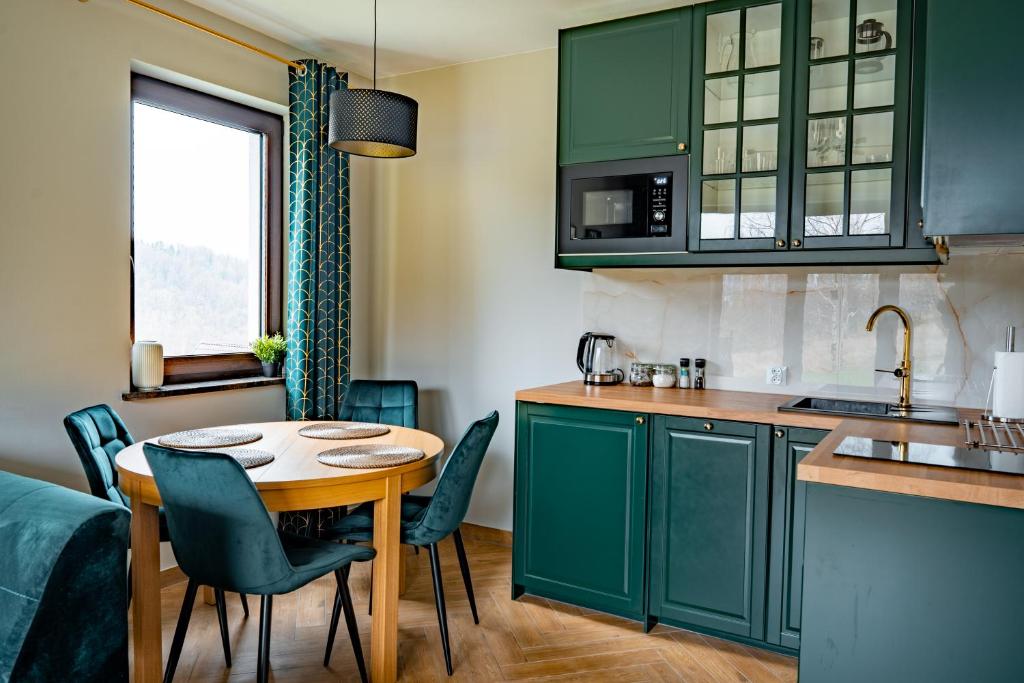 a kitchen with green cabinets and a table and chairs at Apartament na Wzgórzu 3, Sauny, ebike, las, widok - 5D Apartamenty in Świeradów-Zdrój