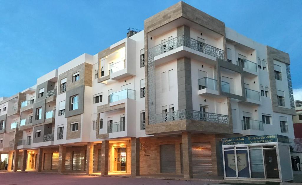 a large white building with balconies on a street at Résidence Palmera Martil in Martil