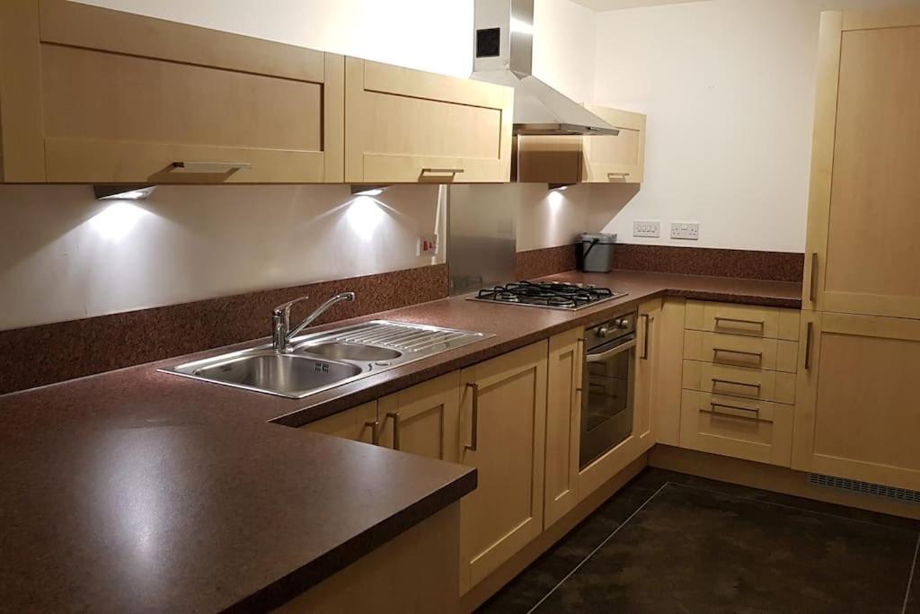 a kitchen with a sink and a stove at Lovely 2-bedroom flat with free parking in Glasgow