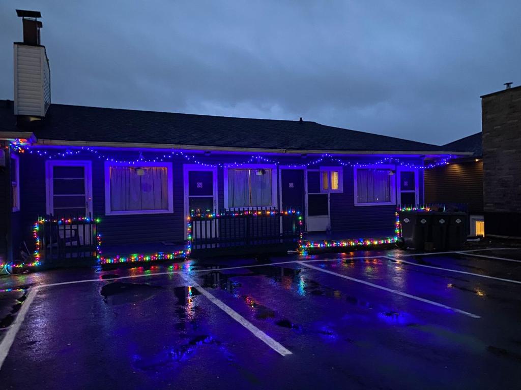 una casa azul con luces de Navidad en un estacionamiento en Hillcrest Motel, en Saint John