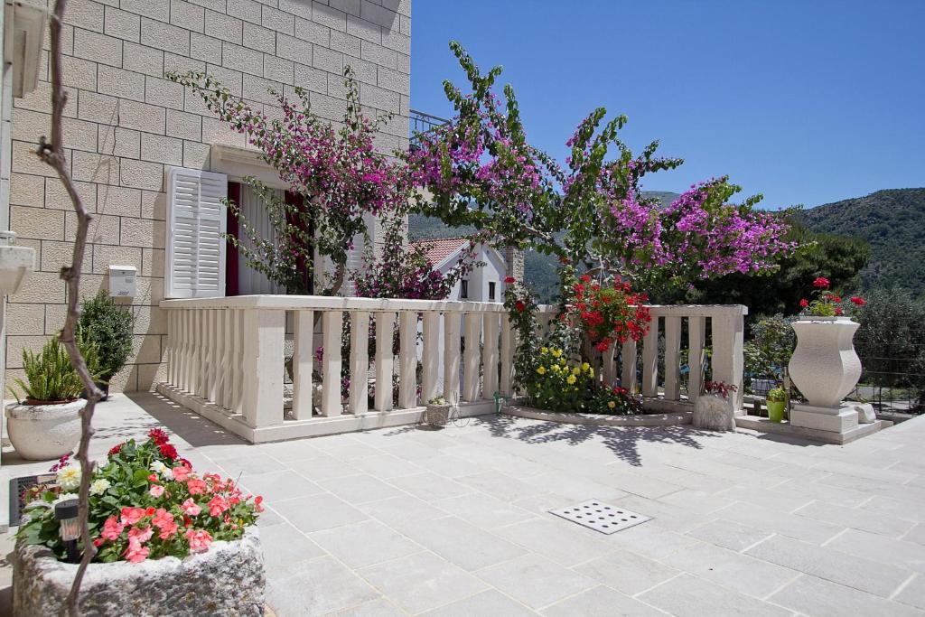 a white fence with flowers in front of a house at Apartments Nine Slano in Slano