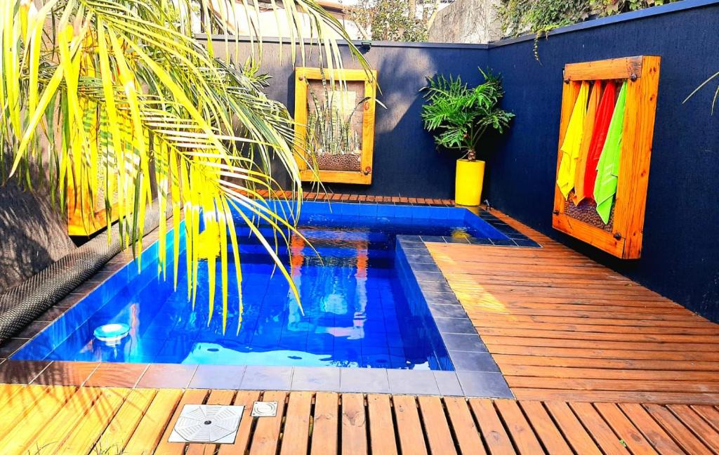 uma pequena piscina com um deque de madeira e uma casa em Bangalô das Lagartixas ,casa stúdio com piscina aquecida privativa a 20 minutos do Centro de Curitiba em Colombo