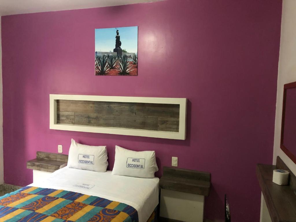 1 dormitorio con pared morada, cama y reloj en Hotel Occidental, en Guadalajara