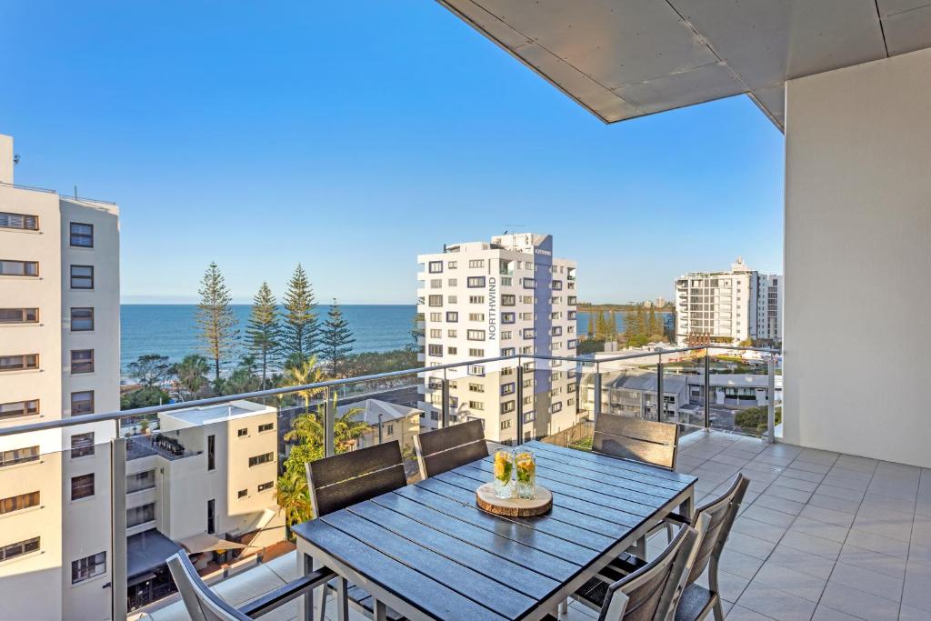 a balcony with a blue table and chairs and the ocean at Coco Mooloolaba in Mooloolaba