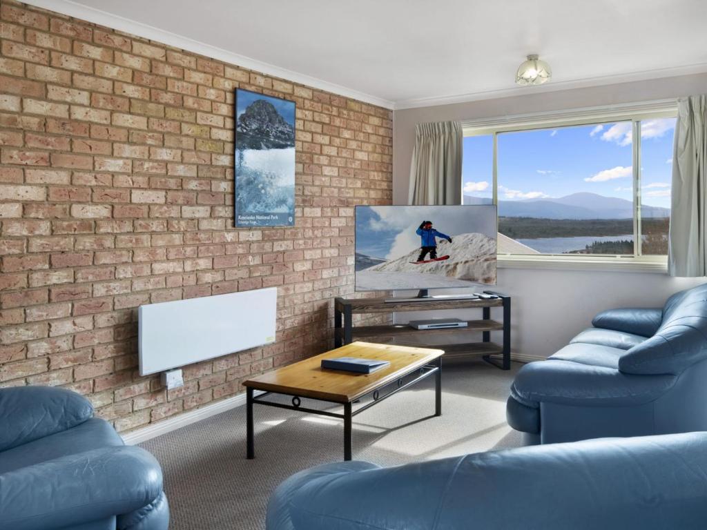 a living room with blue furniture and a brick wall at Beloka 7 Free WiFi in Jindabyne