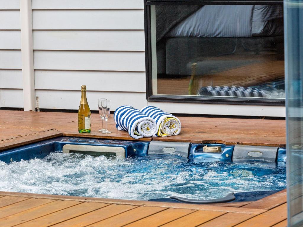 a hot tub on a deck with a bottle and glasses at Kamala Mount Eliza in Mount Eliza