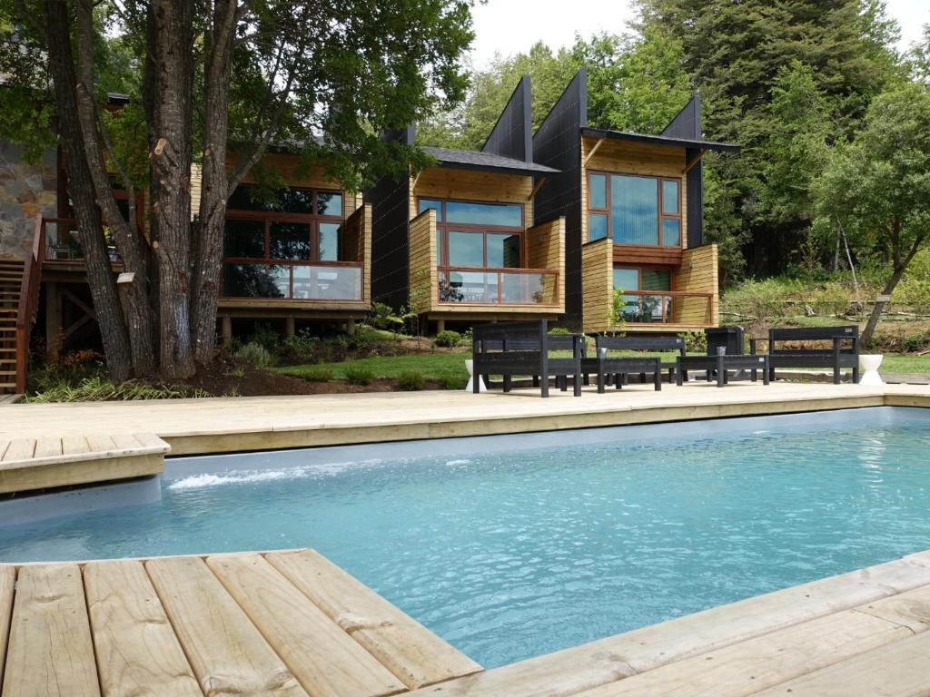 a house with a swimming pool in front of a house at NI-NEWEN Hotel & Lodge in Pucón