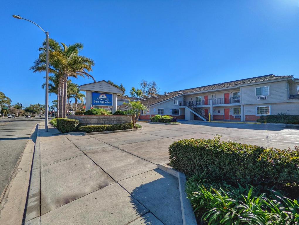 a building with palm trees in front of a street at Americas Best Value Inn Oxnard-Port Hueneme in Port Hueneme