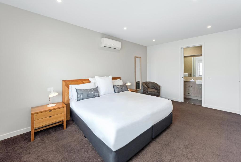 1 dormitorio con 1 cama blanca grande y mesita de noche en Fawkner Executive Suites & Serviced Apartments, en Melbourne