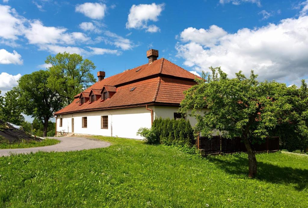 a white house with a red roof on a green field at Hájenka Strakov in Litomyšl