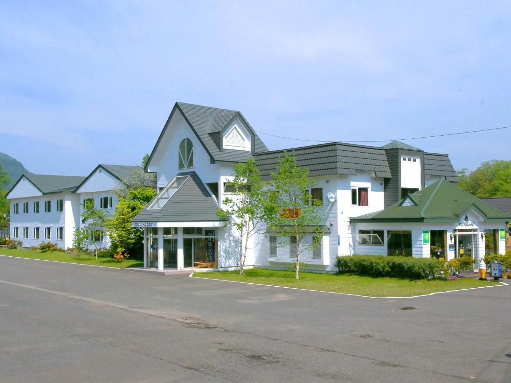 una grande casa bianca con tetto grigio di Hotel Parkway a Teshikaga