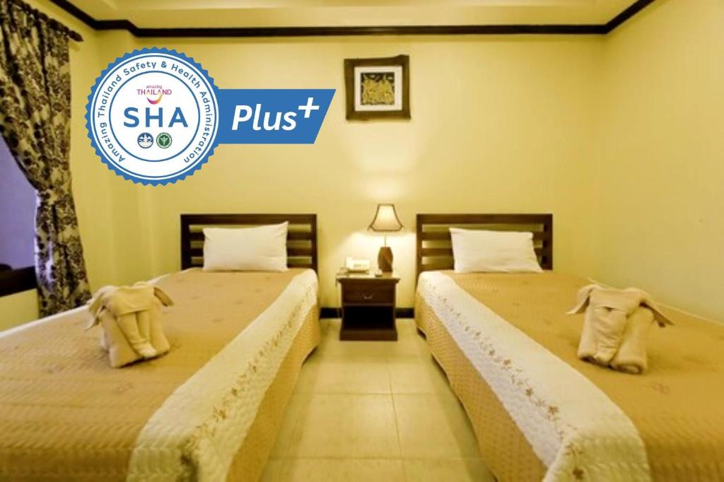 Dos camas en una habitación con un cartel que dice shha plus en Andaman House SHA Plus, en Patong Beach