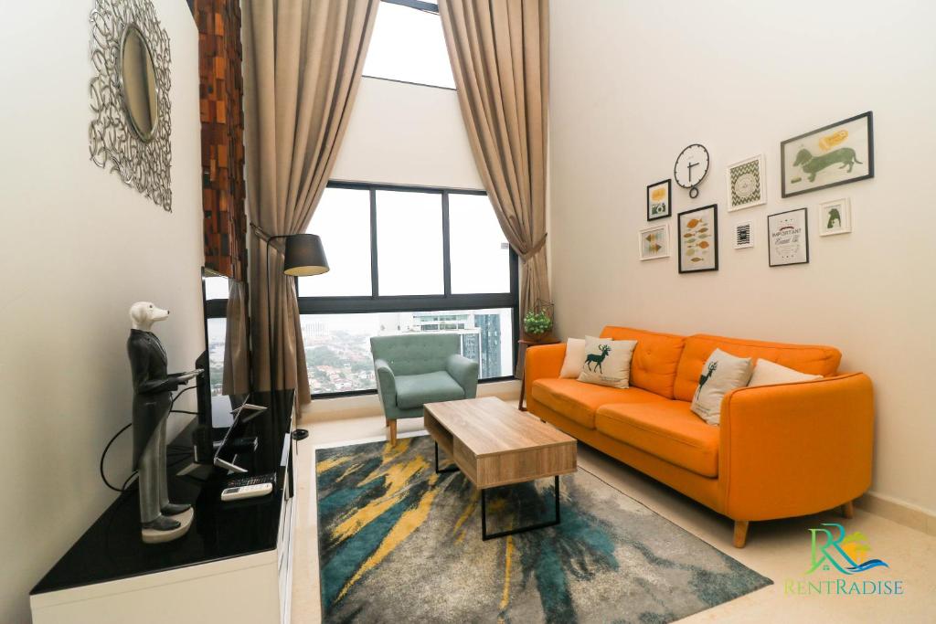 a living room with an orange couch and a television at VSummer Stylish Loft Suites @ UHA in Johor Bahru
