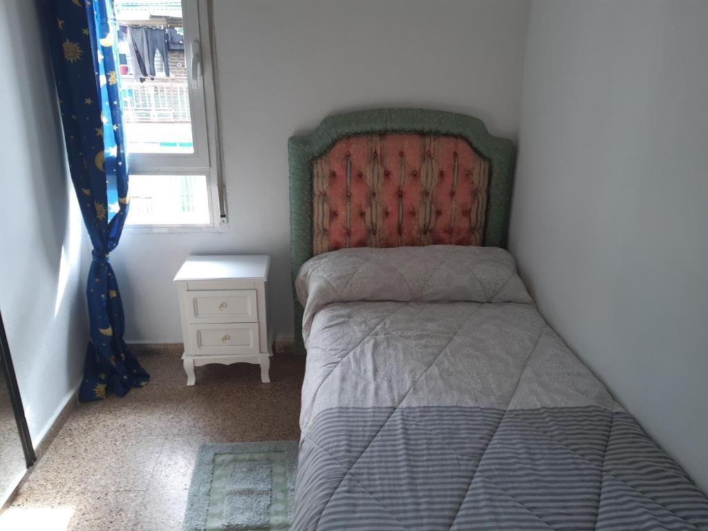 ein kleines Schlafzimmer mit einem Bett und einem Nachttisch in der Unterkunft Room in Guest room - Peaceful accommodation in Madrid near Atocha in Madrid