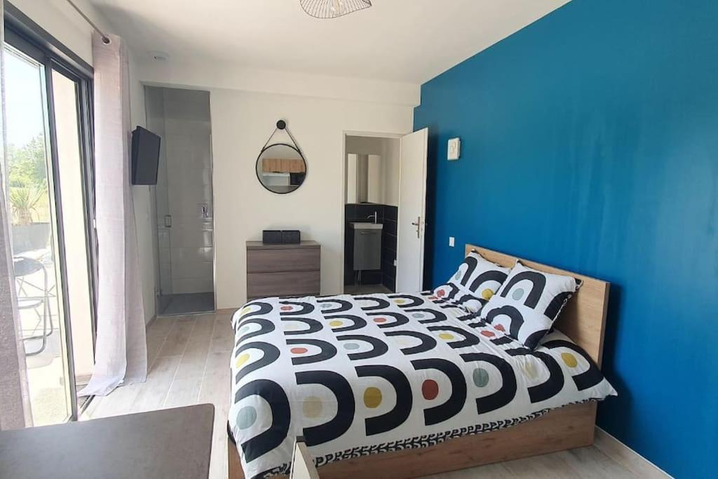a blue bedroom with a bed with a black and white comforter at Studio Provence in Istres