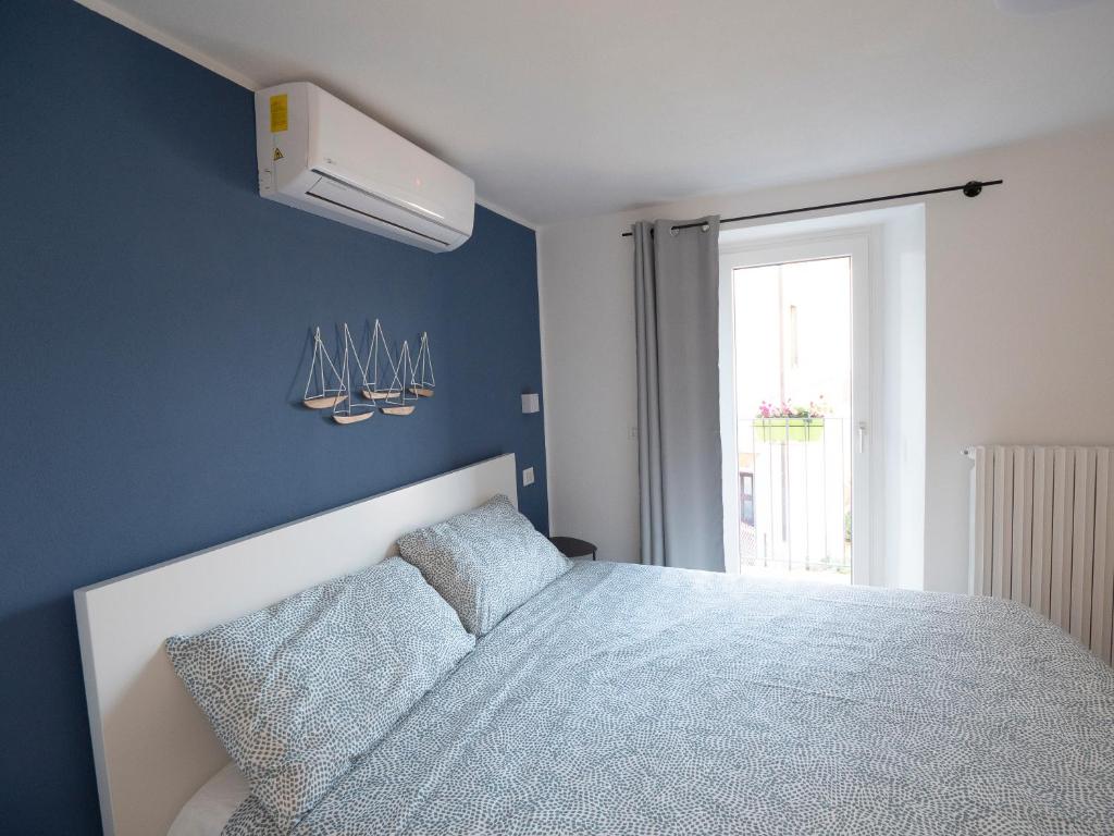 1 dormitorio con 1 cama con pared azul en Bellano Holidays - Casa Artemio en Bellano